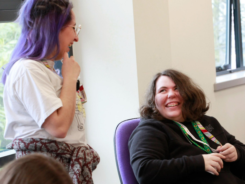 Two colleagues smile and laugh together.