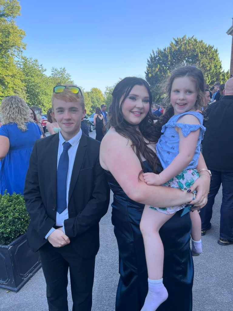 Three siblings in fancy clothes looking and smiling at the camera