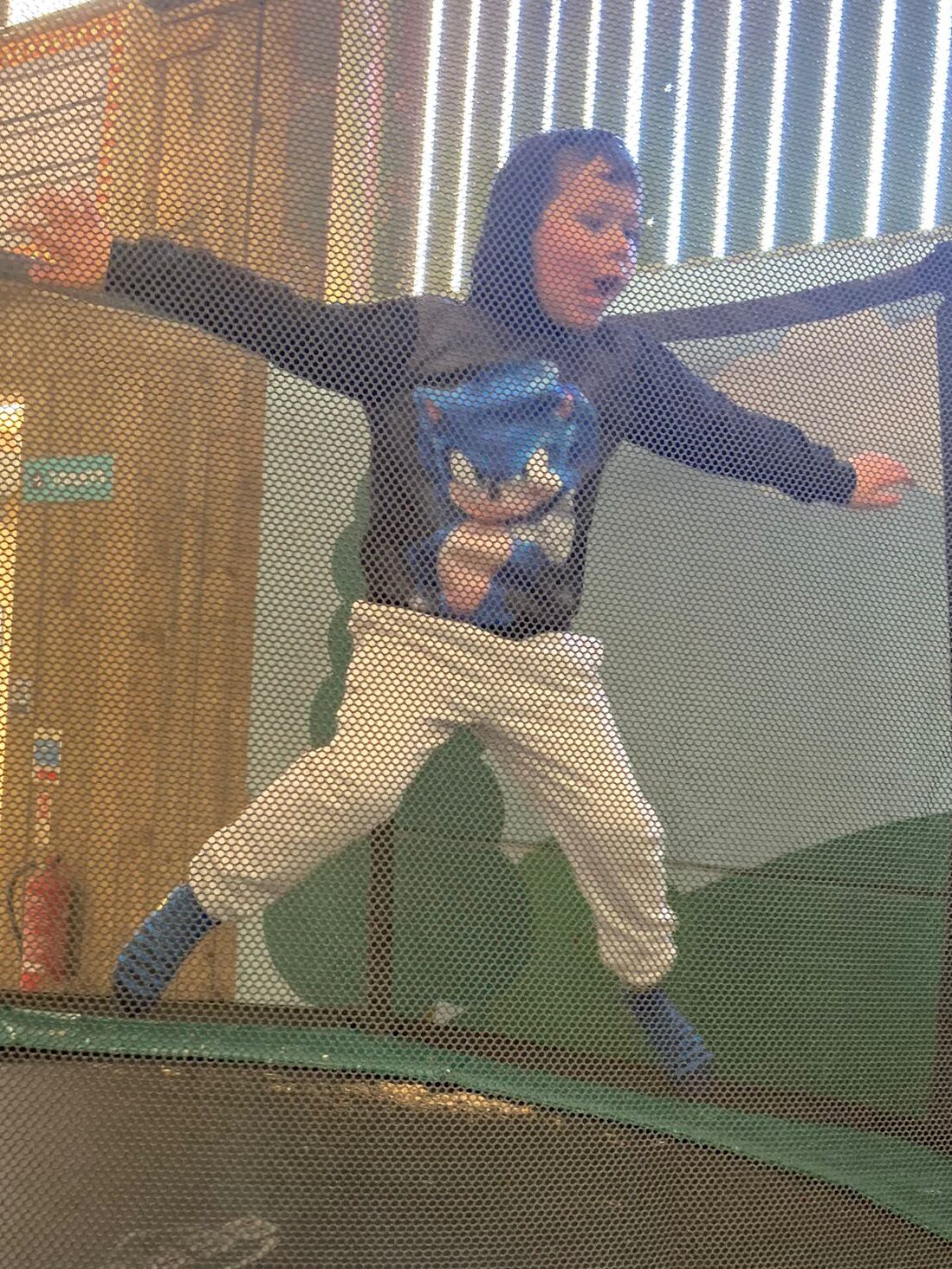 Cody is mid-air after bouncing on the trampoline at Tapnell Farm Park. He is wearing a hoodie with Sonic the Hedgehog on it.