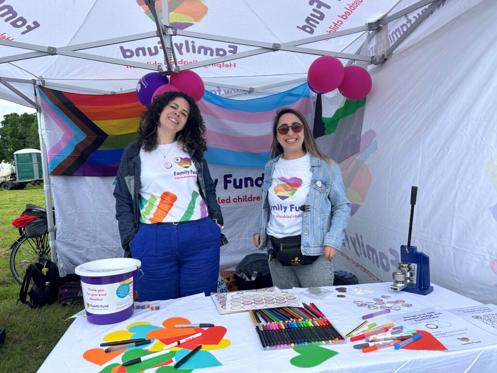 Two women wearing Family Fund t-shirts stand at the Family Fund York Pride stall.