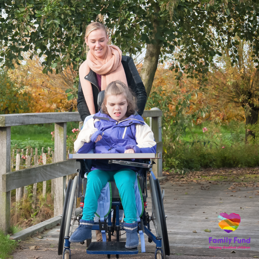 A young child in a wheelchair and her carer