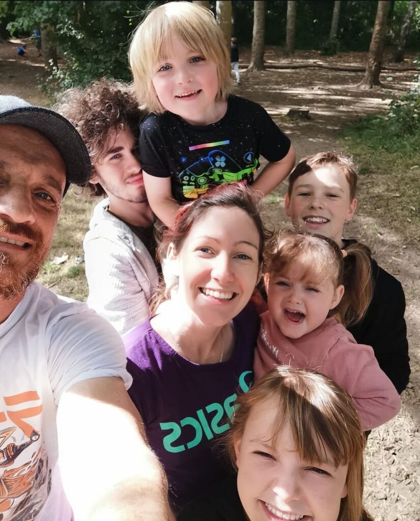 A photo of Charlotte with her mum, siblings and family friends walking in the park.