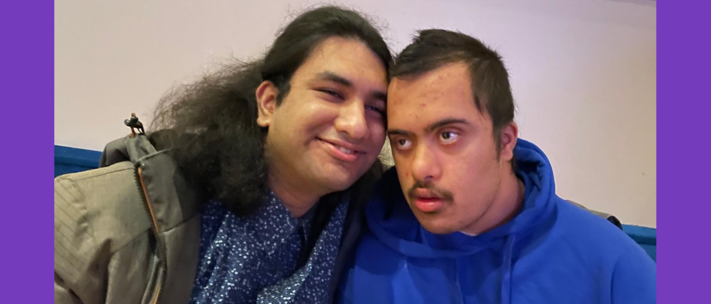 Agnijo presses his face against his brother, Aaryan's. Aaryan is looking to the side, wearing a blue hoodie. Agnijo is looking at the camera and smiling, in a blue jumper and coat.