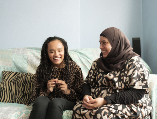 A child and her mum sitting on a sofa.