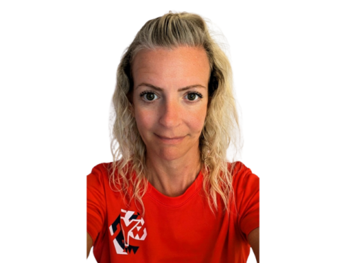 A woman with blonde wavy hair smiles, wearing a red top