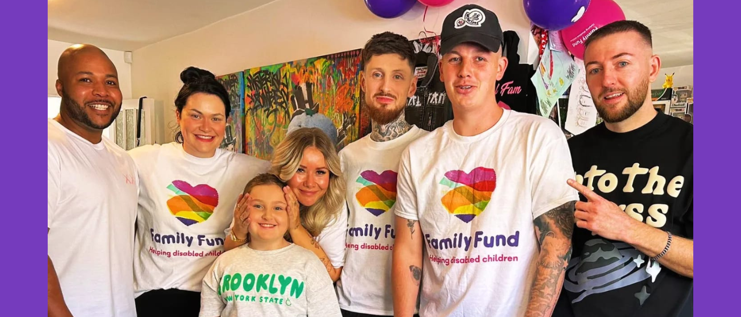 A team of people stand together wearing Family Fund t-shirts. There are balloons and there are streamers in the background. Everyone is happy or smiling.