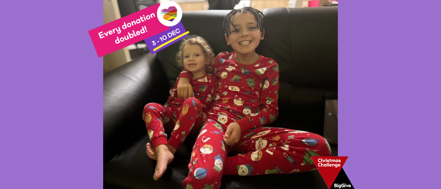 A young girl and her older brother sitting smiling on a black sofa together wearing matching red Christmas pyjamas. A pink banner is in the top left with text 'every donation double 3-10 Dec!'