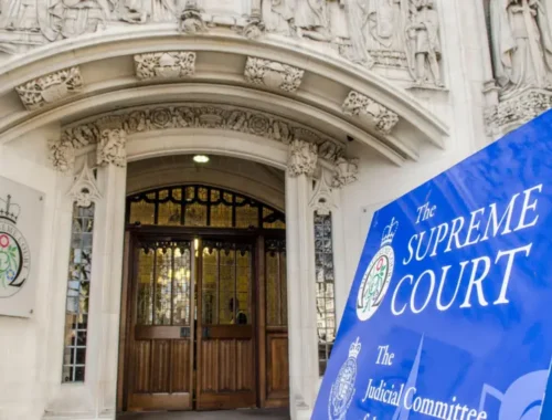 Front entrance of the UK Supreme Court, with a blue board in front that says 'The Supreme Court'.