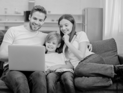 a family sat on a sofa looking at a laptop