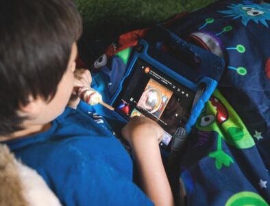 A young boy sat in bed using his tablet