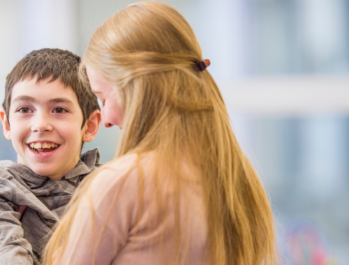 a young boy smiling being held and cuddling an adult woman