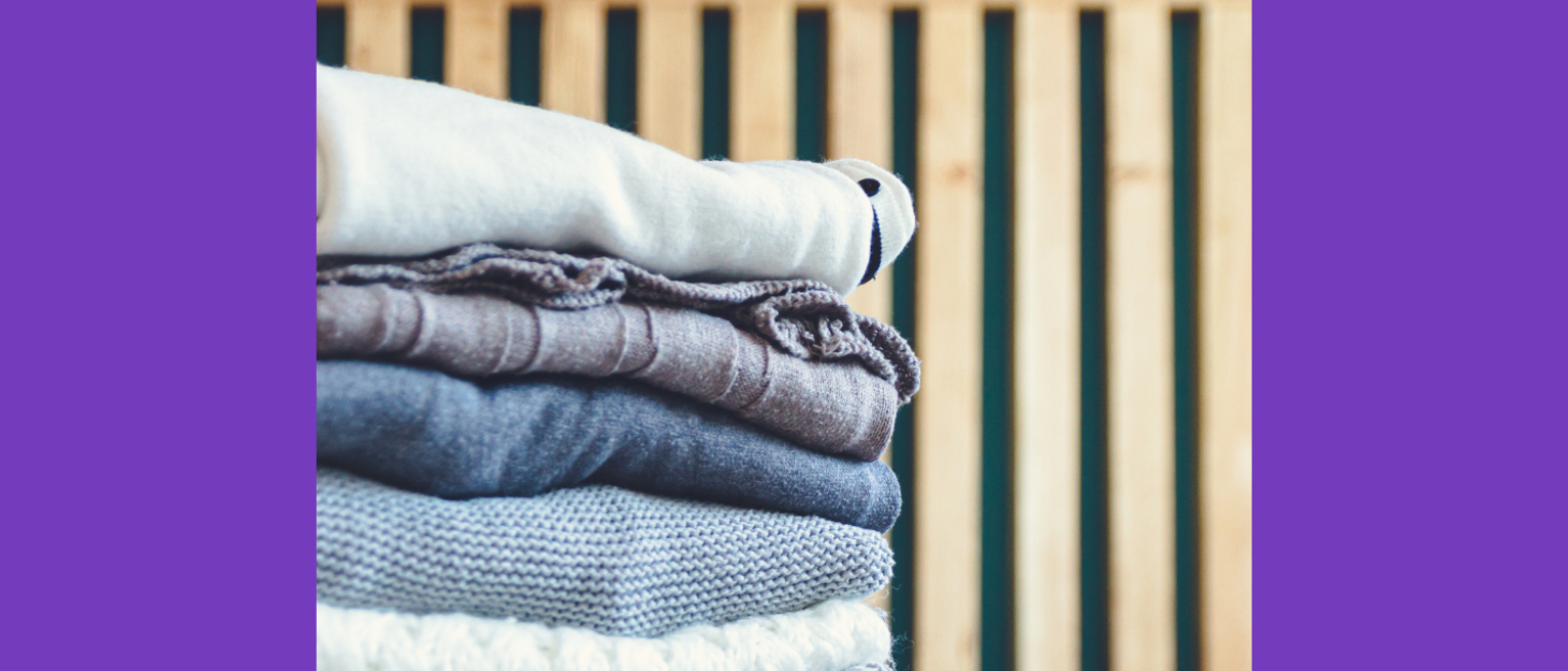 Pile of clothes lies folded on bed