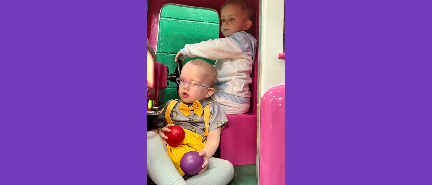 Brothers Noah and Eli sitting in outdoor play equipment